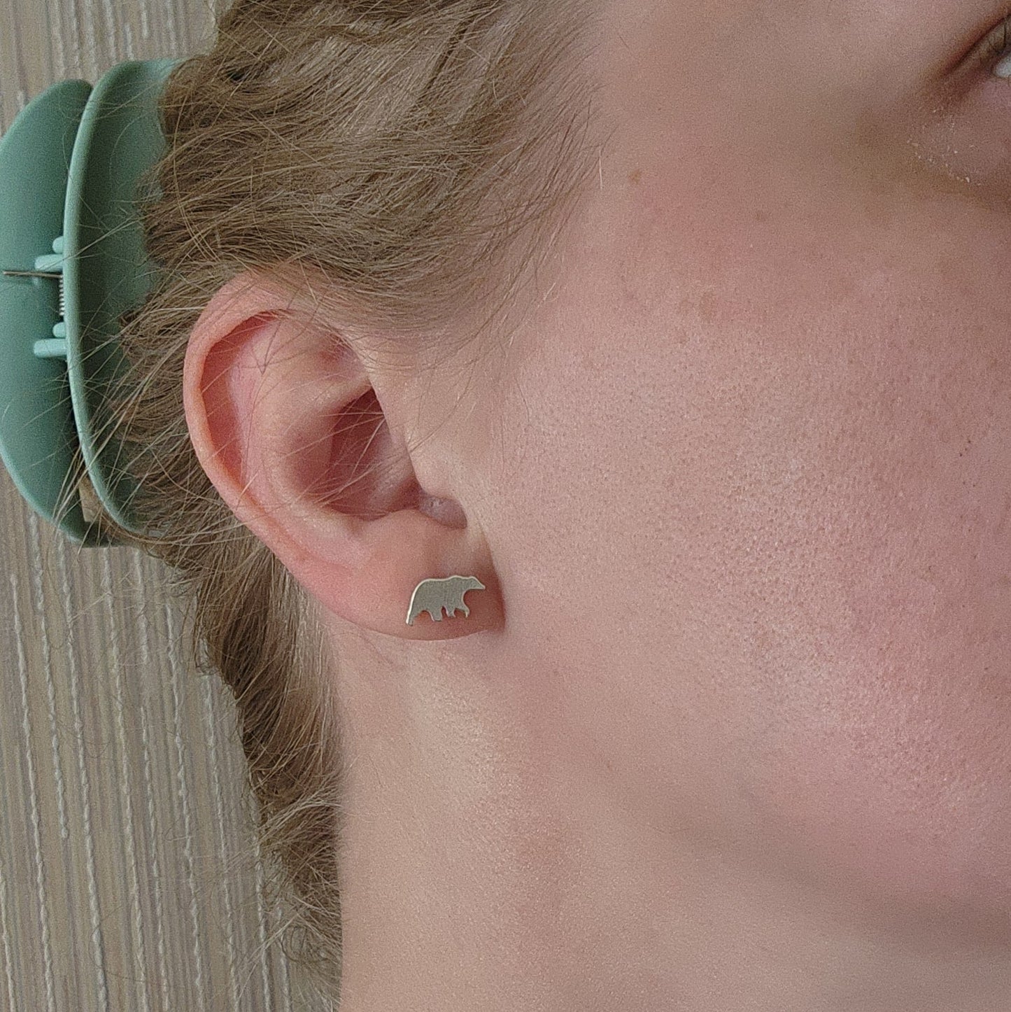 sterling silver bear stud earrings with silicone backs, shown in right ear with bear facing towards face