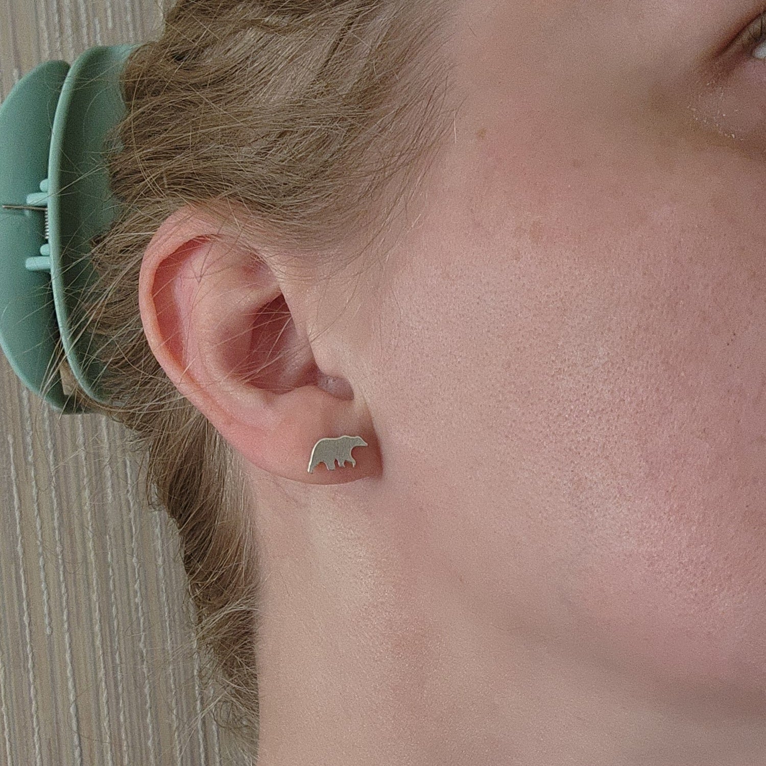 sterling silver bear stud earrings with silicone backs, shown in right ear with bear facing towards face